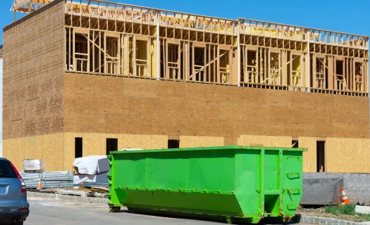Commercial green roll-off dumpster placed at a construction site for business waste removal in Dallas