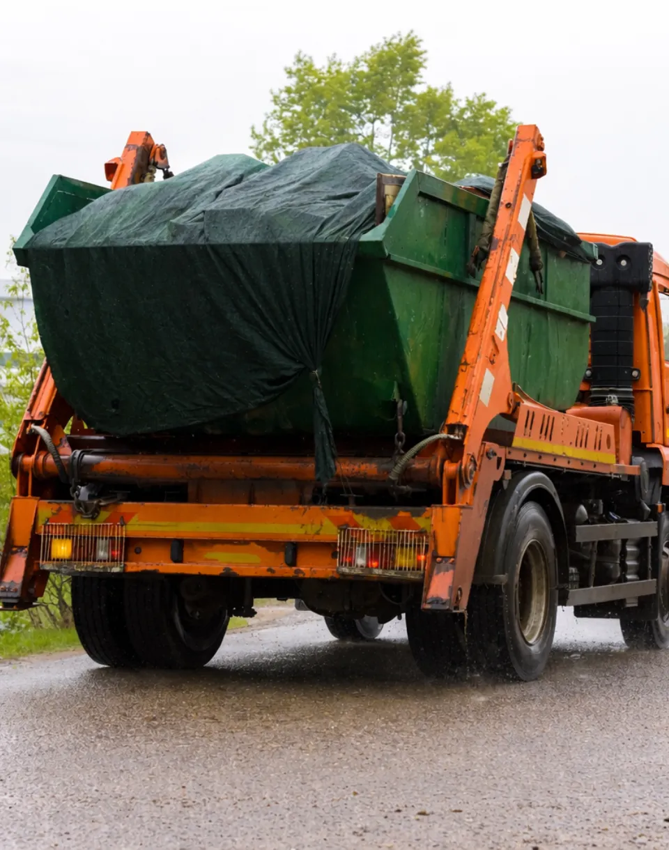 Dump Pro Dallas hauling a green roll-off dumpster during scheduled pickup