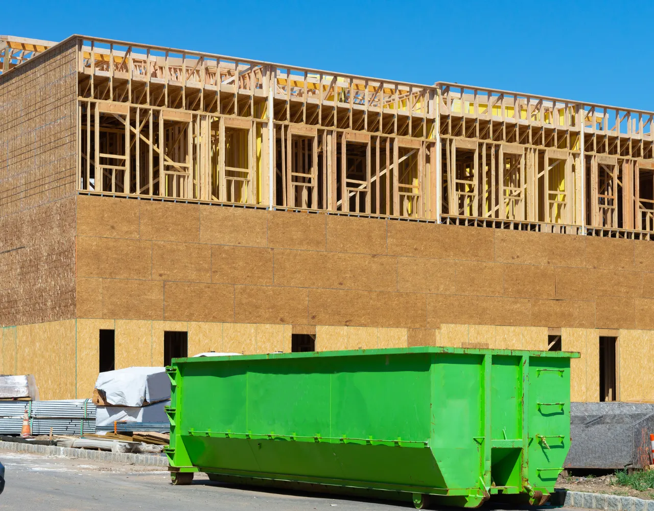 Commercial green roll-off dumpster placed at a construction site for business waste removal in Dallas