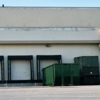 Commercial dumpster placed at a warehouse loading dock for business waste management