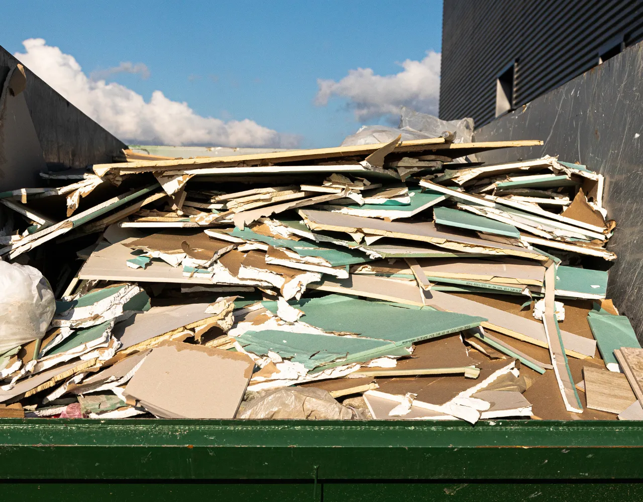 Open green roll-off dumpster loaded with construction debris and scrap metal for hauling in Dallas